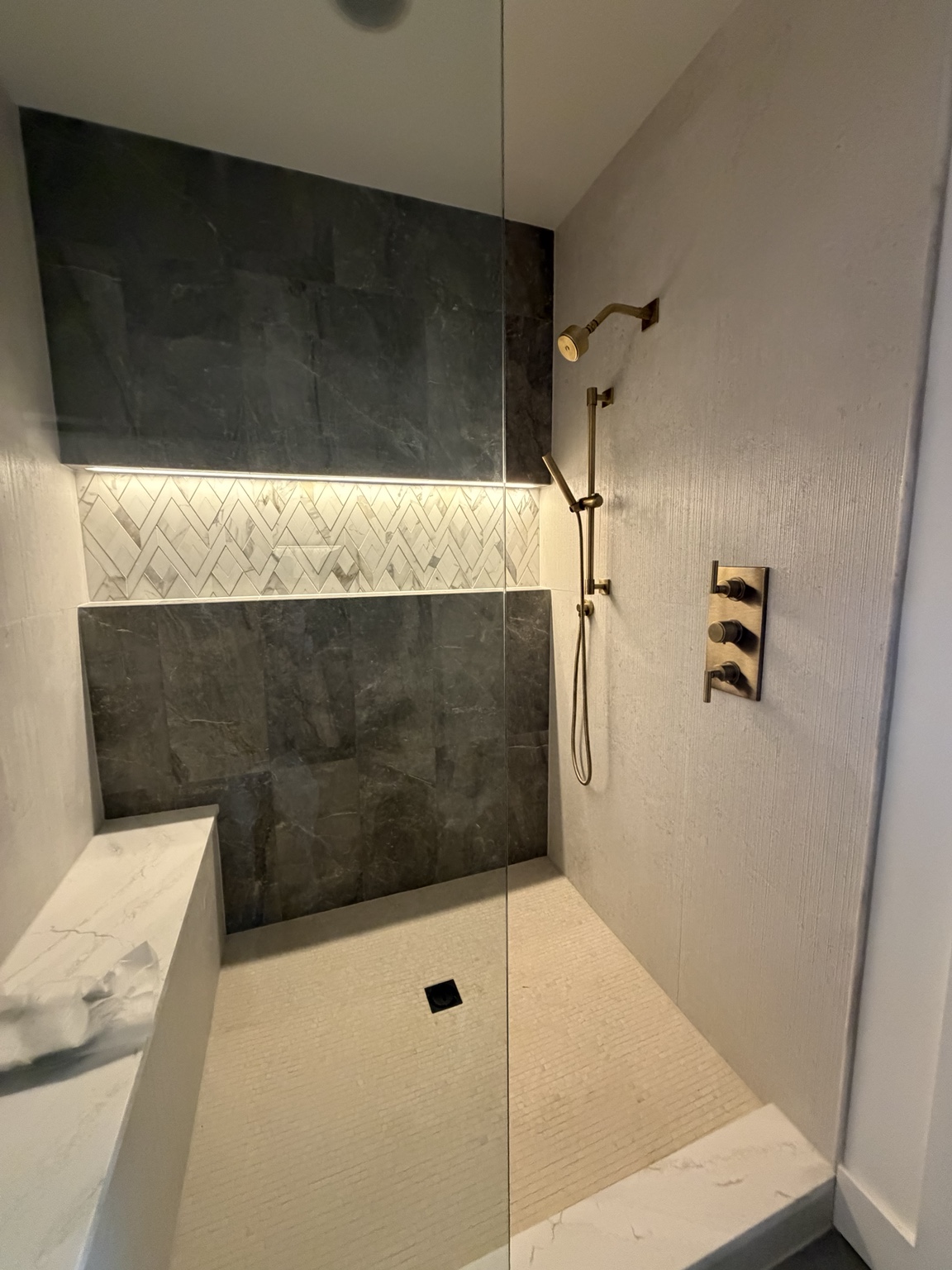 Completed walk-in shower remodel with rain head, handheld shower, and glass enclosure