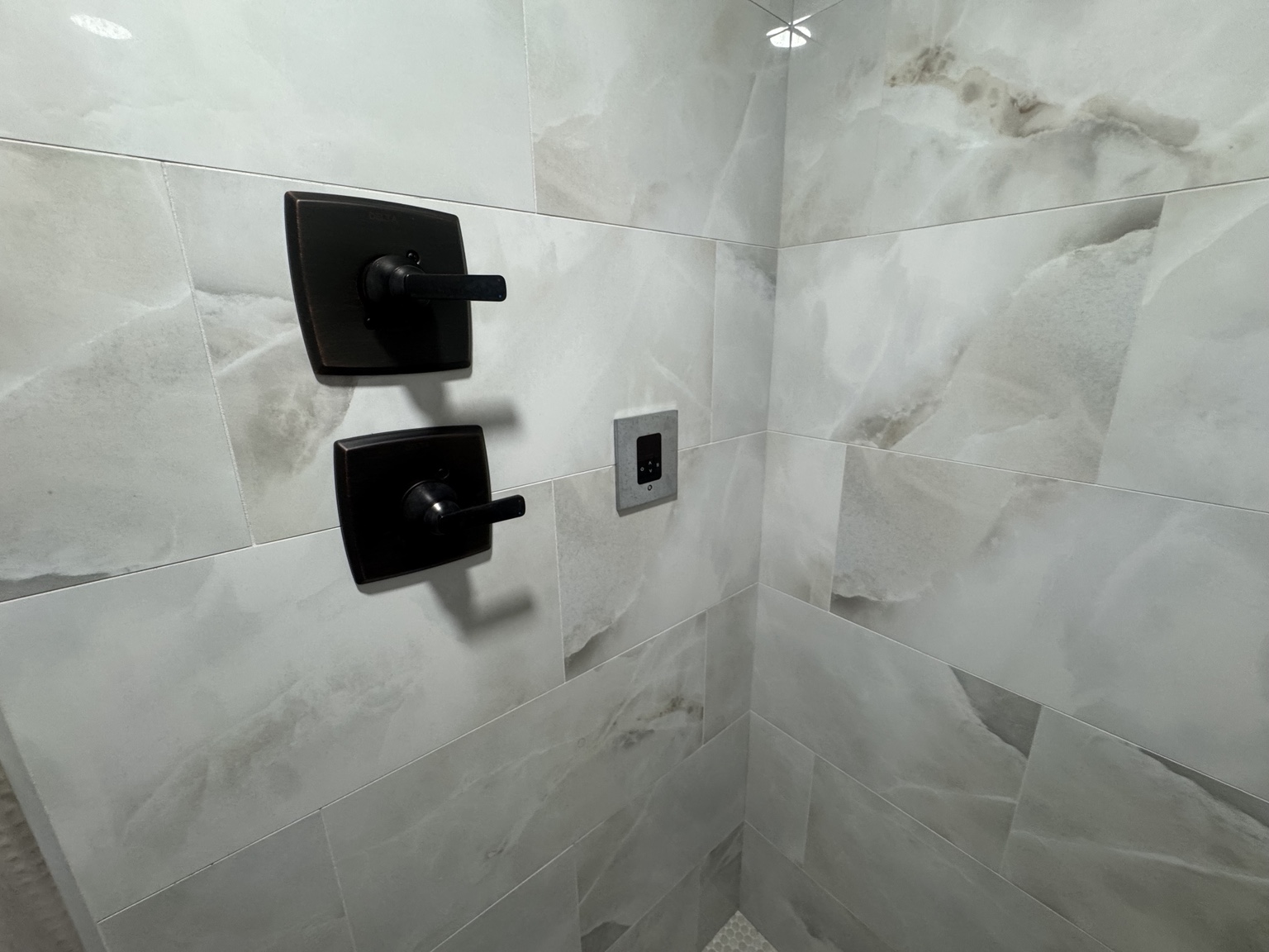 Finished custom tiled shower with black controls and steam shower controller